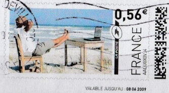 Man with his feet up on the beach watching his laptop