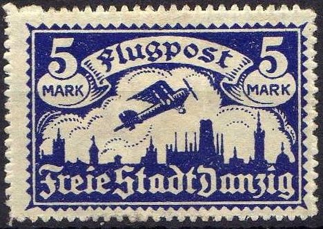 Airplane flying over the silhouette of the skyline of Danzig